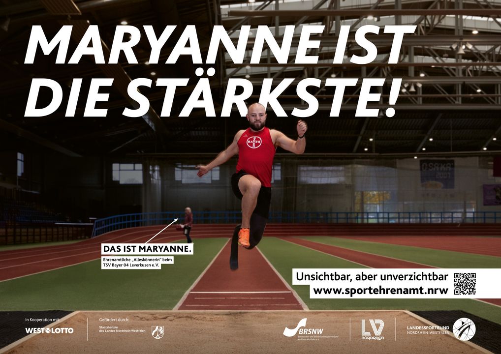 Ein Para-Leichtathlet beim Weitsprung in der Halle. Im Hintergrund überreicht die Ehrenamtliche des TSV Bayer 04 Leverkusen, Maryanne, einen Picknickkorb zur Stärkung. Aufdruck: ‚Maryanne ist die Stärkste!‘ – Teil der Offensive #SPORTEHRENAMT. Sichtbarmachung des oft übersehenen Ehrenamts im Sport. – Format 594x420