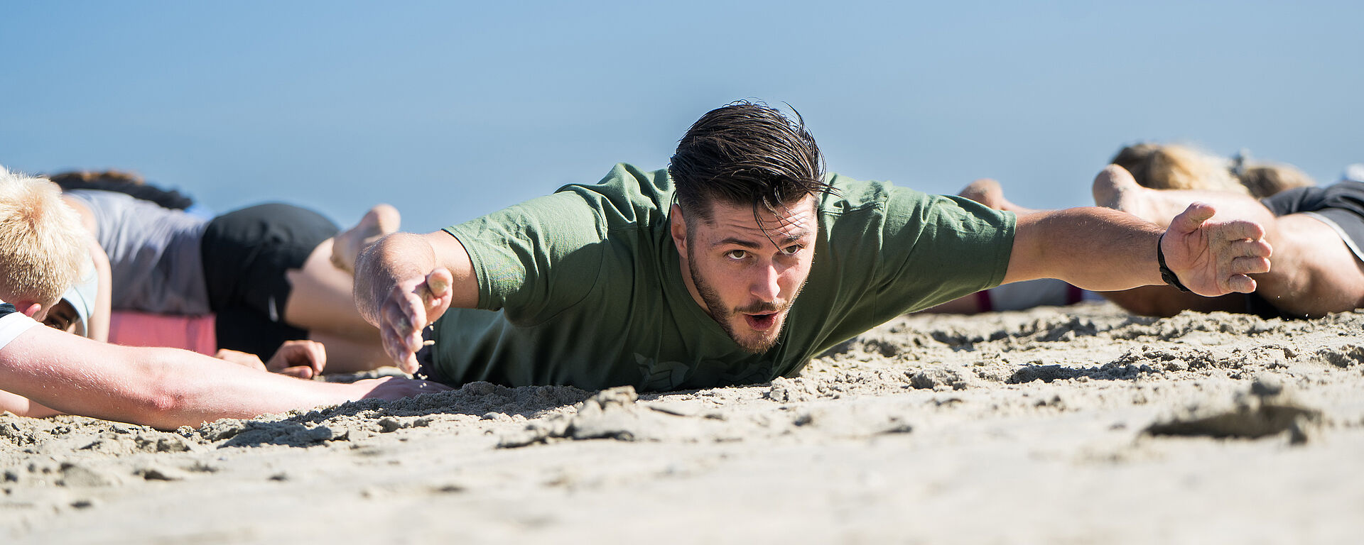 Kopfbild: Sportler mit Gruppe am Strand