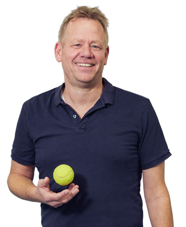 Mann mit blauem Poloshirt spielt mit einem Tennisball in seiner rechten Hand.