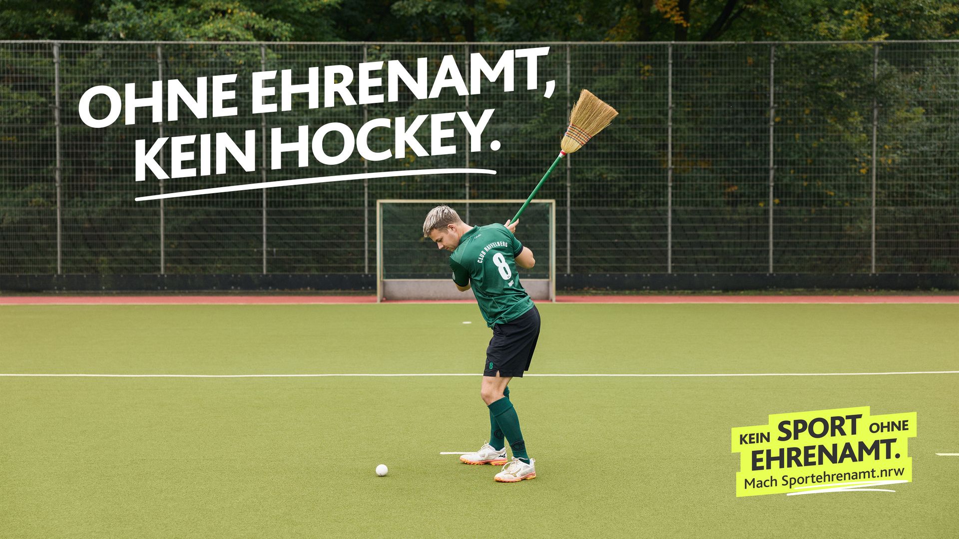Hockeyspieler versucht mit einem Besen einen Ball zu schlagen. Darüber in weißer Schrift: „Ohne Ehrenamt, kein Hockey.” Motiv der LSB NRW Offensive 2026 zum Sportehrenamt mit dem Claim „Kein Sport ohne Ehrenamt“ und dem Aufruf „Mach Sportehrenamt.nrw“.