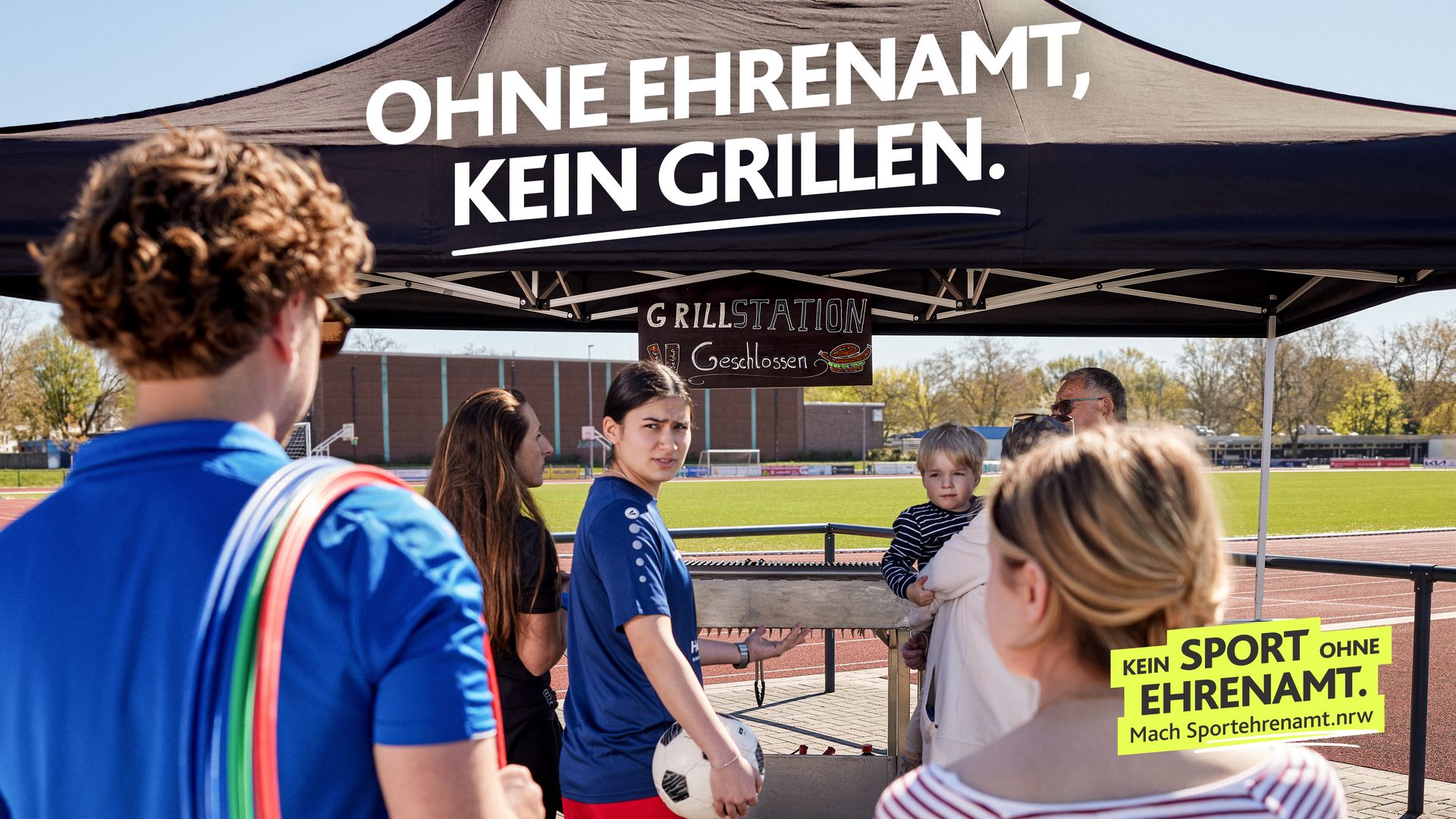 Eine Gruppe Sportlerinnen und Sportler steht vor einer geschlossenen Grillstation auf dem Vereinsgelände. Darüber steht „Ohne Ehrenamt, kein Grillen“. Motiv Grillstation der LSB NRW Offensive 2026 mit dem Claim „Kein Sport ohne Ehrenamt. Mach Sportehrenamt.nrw“.